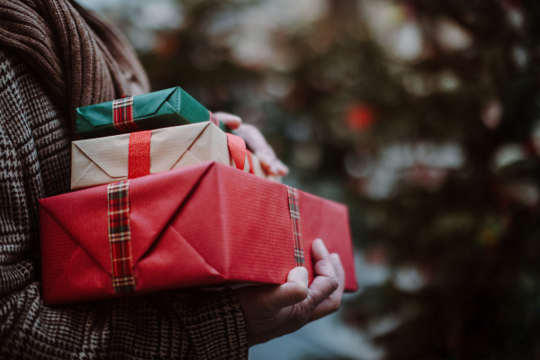 Close-up of man holding the gifts, outdoor at Christmas market.