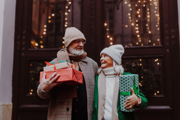 Happy senior couple enjoying outdoor christmas market, buying gifts.