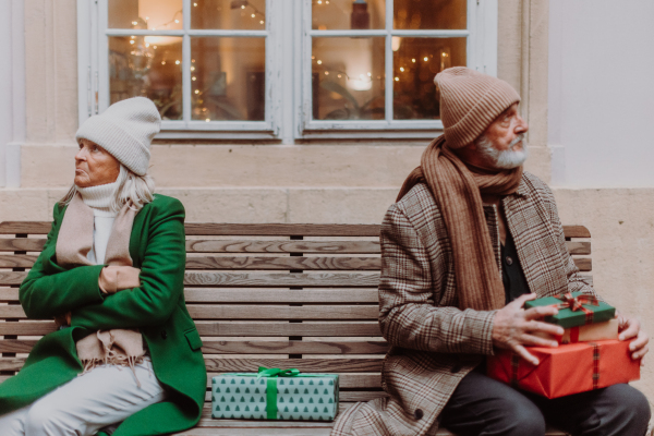 Offended senior couple citting on a city bench. Spouses having christmas family argument.