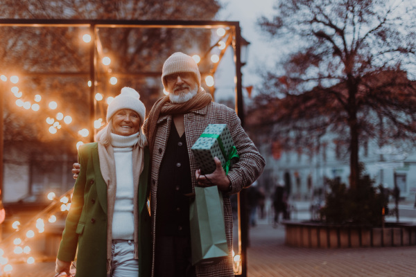 Happy senior couple enjoying outdoor christmas market, buying gifts.