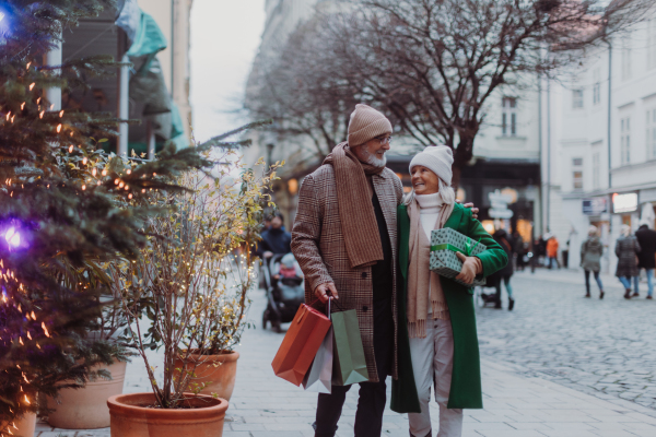 Happy senior couple buying christmas gifts in the winter city streets.