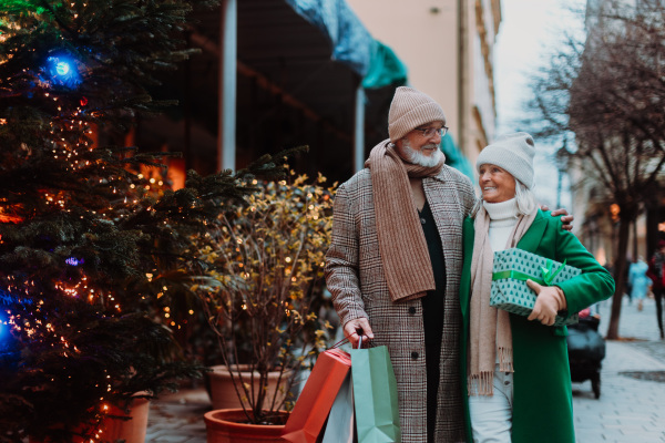 Happy senior couple enjoying outdoor christmas market, buying gifts.