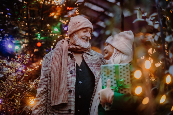 Happy senior couple enjoying outdoor christmas market, buying gifts.