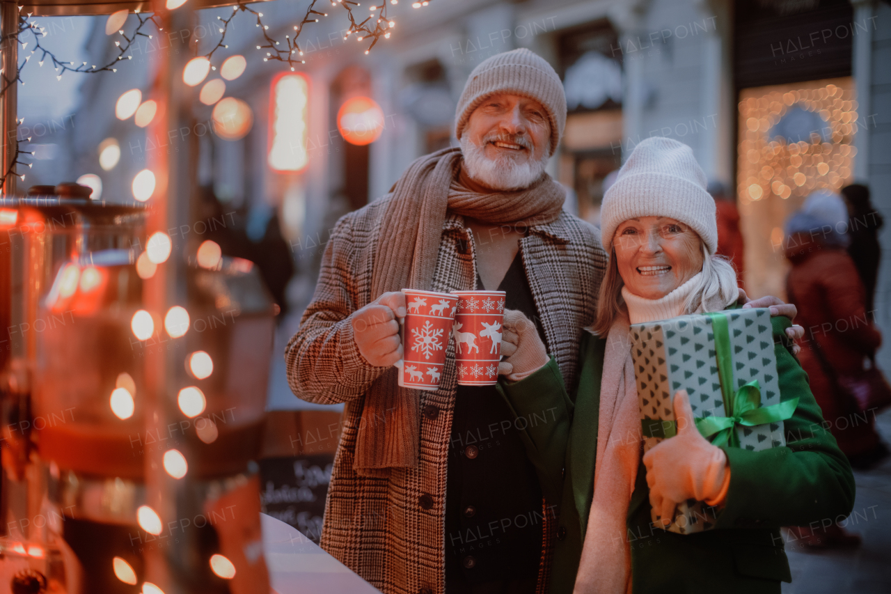 Happy senior couple enjoying outdoor christmas market, buying gifts.