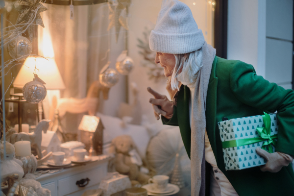 Senior woman looking in window display with a Christmas decorations.