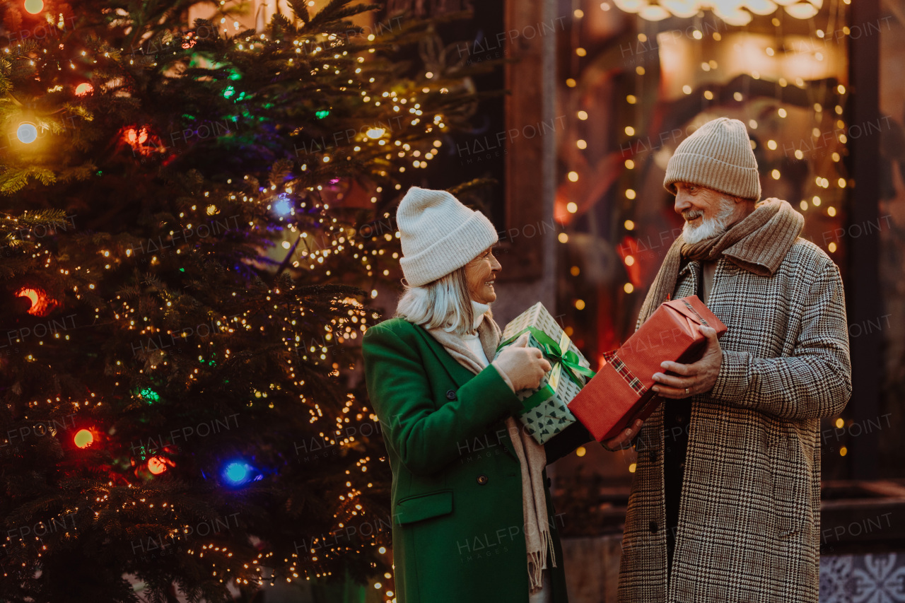 Happy senior couple enjoying outdoor christmas market, buying gifts.