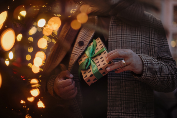 Close-up of man hidding small gift in a pocket, outdoor at Christmas market.