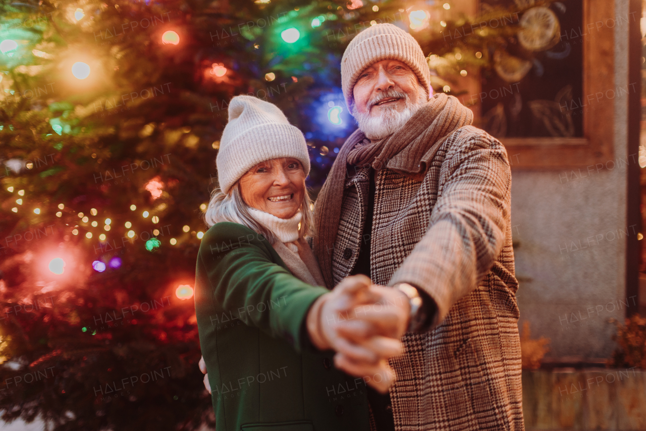 Happy senior couple enjoying outdoor christmas market at the evening, having fun, meeting friends.