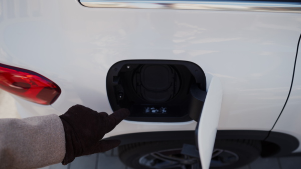 Close up of a senior woman charging electric car.