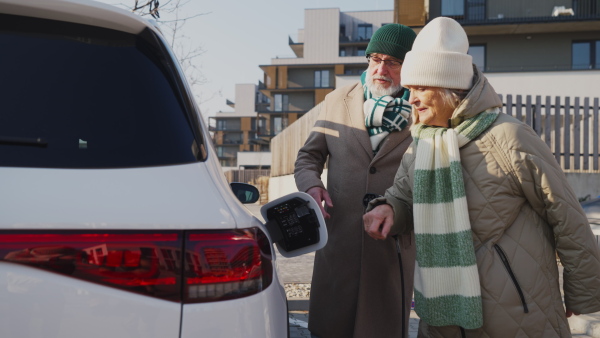 A senior couple charging electric car.