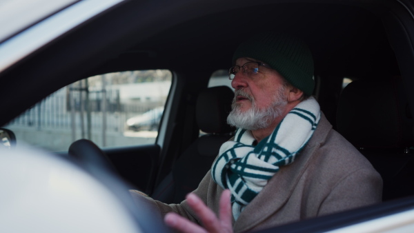 Angry senior man driving a car, close-up.