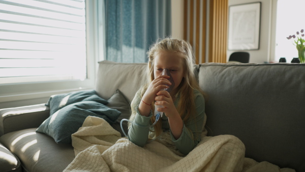 LIttle sick girl using an inhaler during flu.