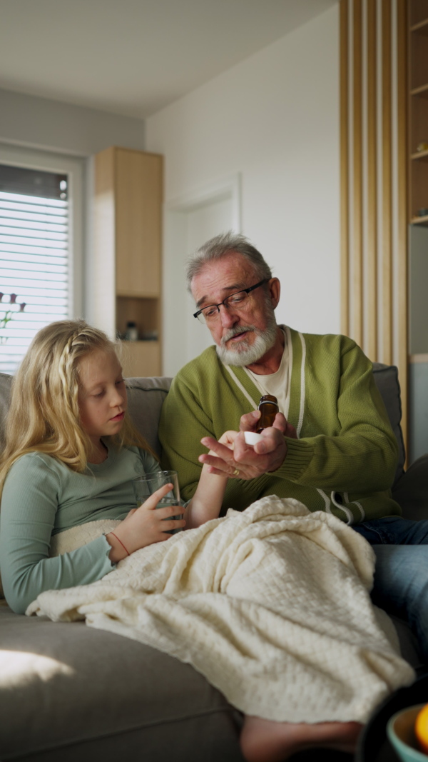 A vertical view of a senior man taking care of his sick granddaughter.