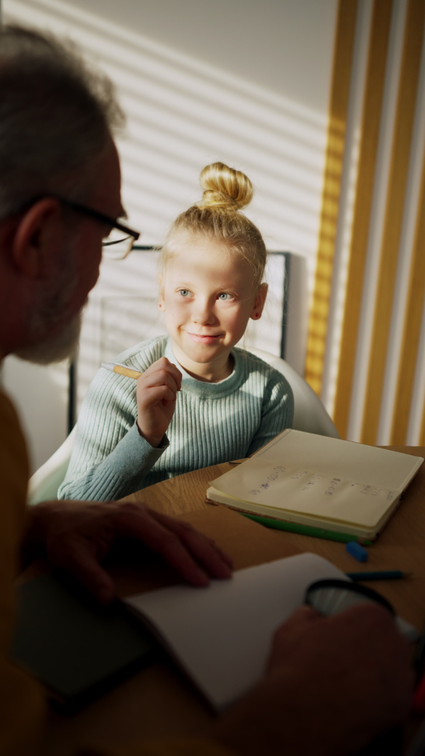 Vertical view of a senior man doing homework with his little granddaughter.