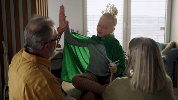 Grandparents playing with their little granddaughter at home.