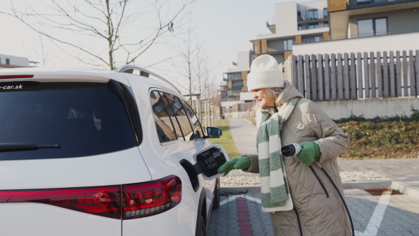 A senior woman charging electric car.