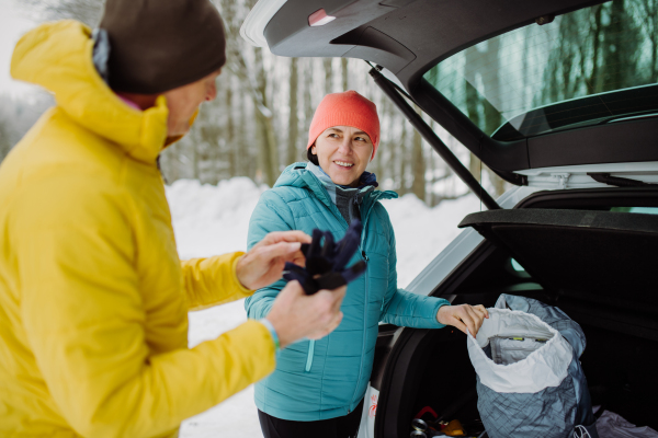 Senior couple near a car trunk preparing for winter hiking.