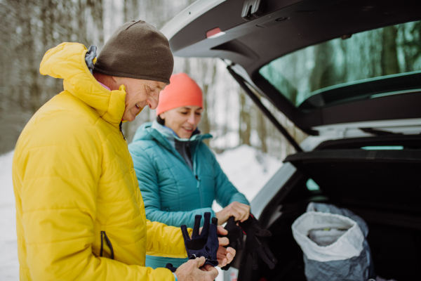 Senior couple near a car trunk preparing for winter hiking.