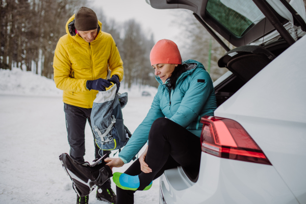 Senior couple near a car trunk preparing for winter skiing.