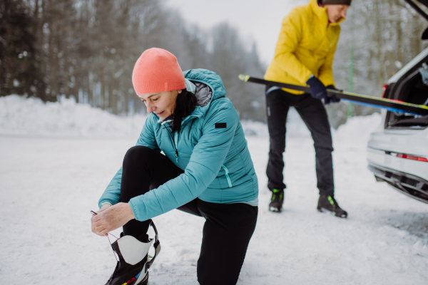 Senior couple near a car trunk preparing for winter skiing.