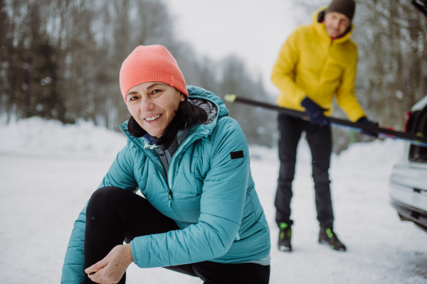 Senior couple near a car trunk preparing for winter skiing.