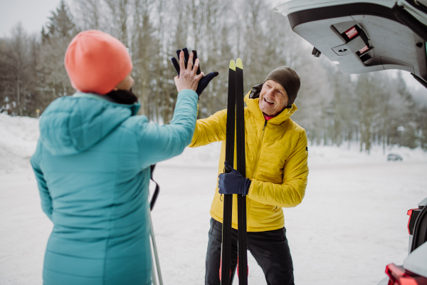 Senior couple near a car trunk preparing for winter skiing.