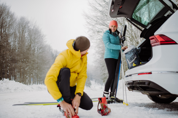 Senior couple near a car trunk preparing for winter skiing.