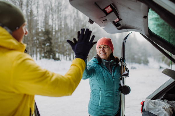 Senior couple near a car trunk preparing for winter skiing.