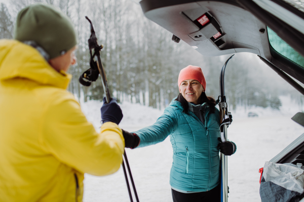 Senior couple near a car trunk preparing for winter skiing.