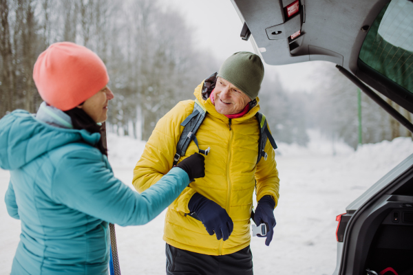 Senior couple near a car trunk preparing for winter hiking.