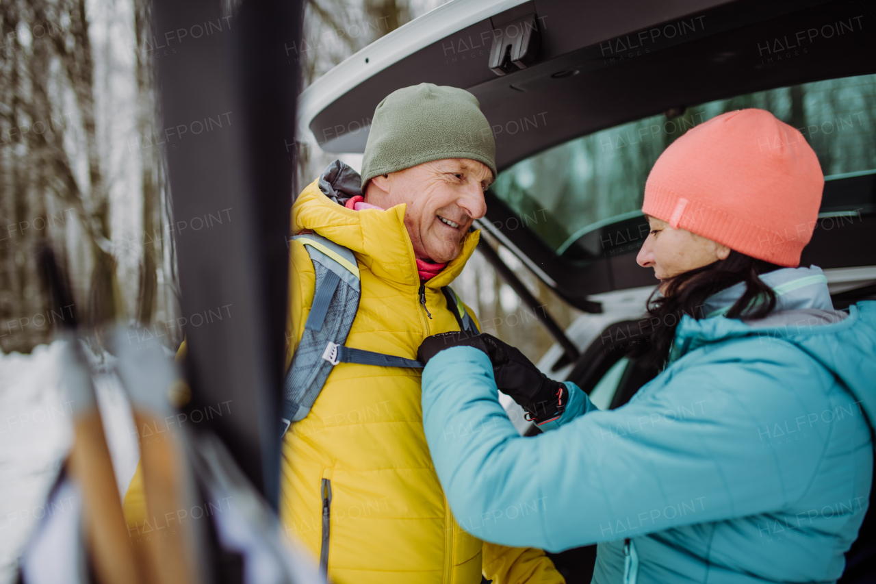 Senior couple near a car trunk preparing for winter skying.