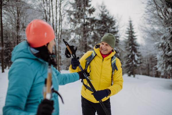 Senior couple skiing together in the middle of snowy forest