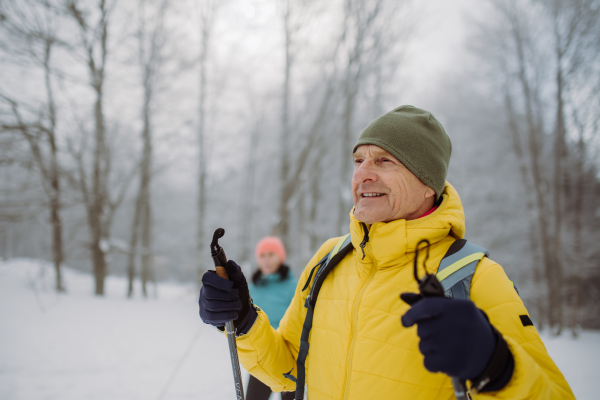 Senior man admiring the nature during cross country skiing with his wife.