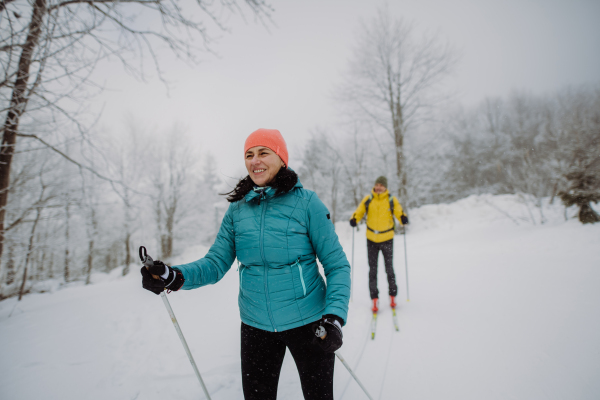 Senior couple skiing together in the middle of snowy forest