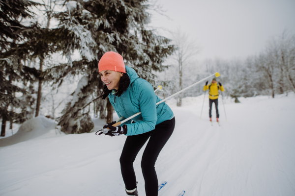 Senior couple skiing together in the middle of snowy forest