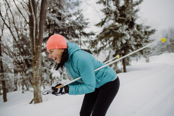 Senior woman skiing alone in the middle of snowy forest.