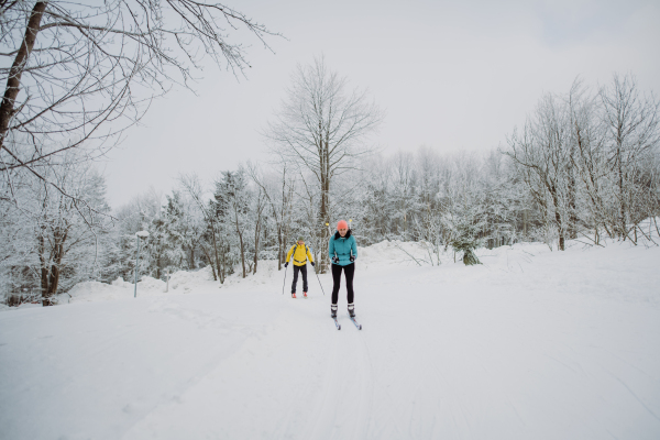 Senior couple skiing together in the middle of snowy forest