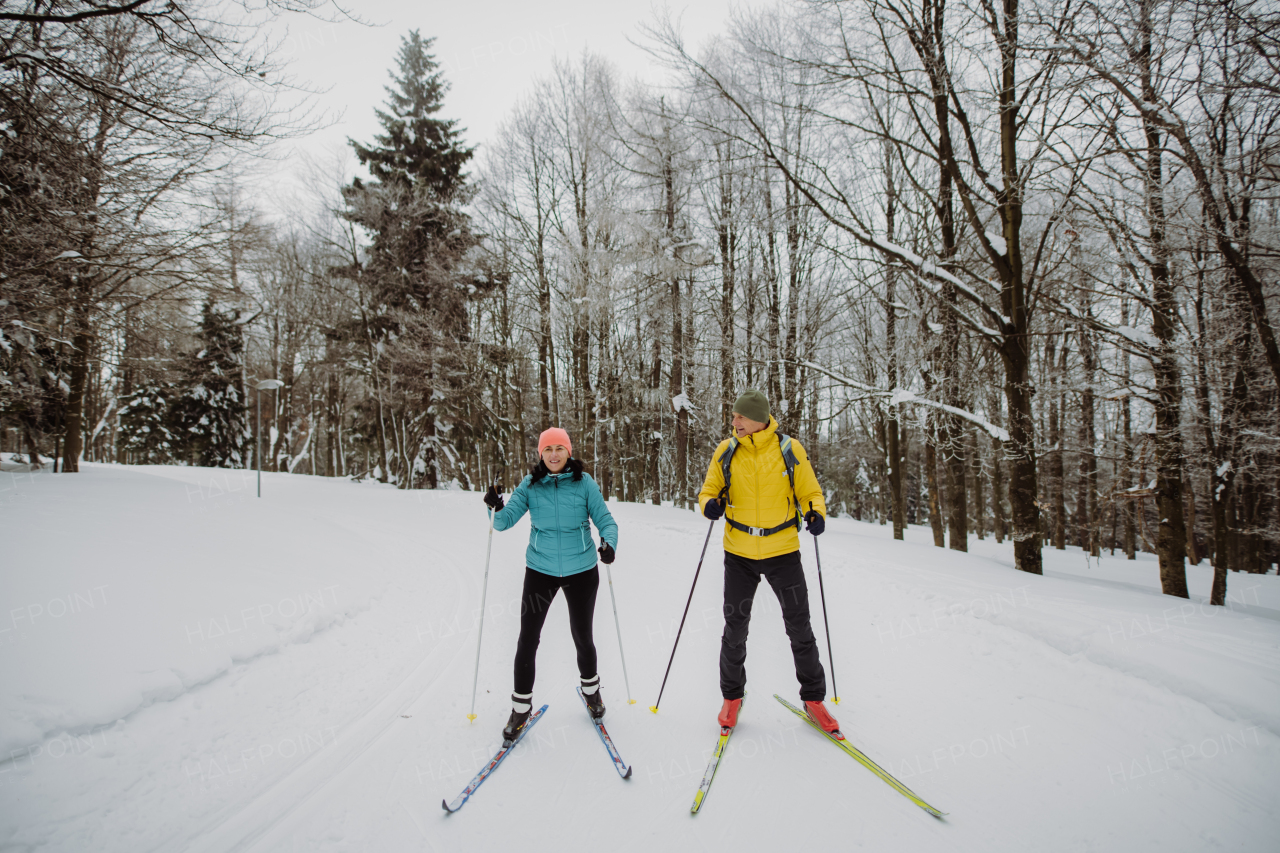 Senior couple skiing together in the middle of snowy forest