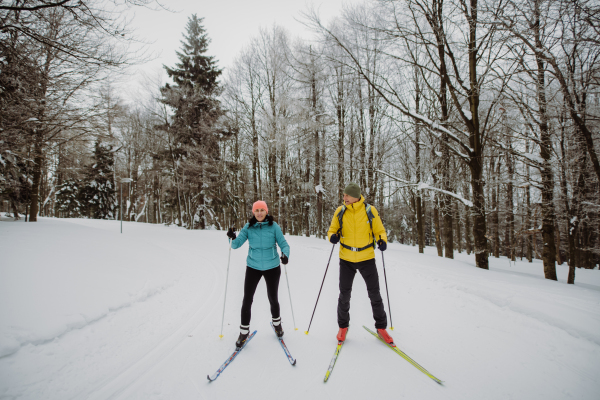 Senior couple skiing together in the middle of snowy forest