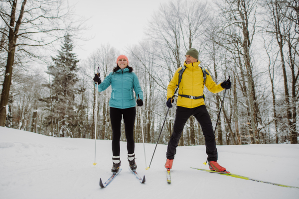 Senior couple skiing together in the middle of snowy forest