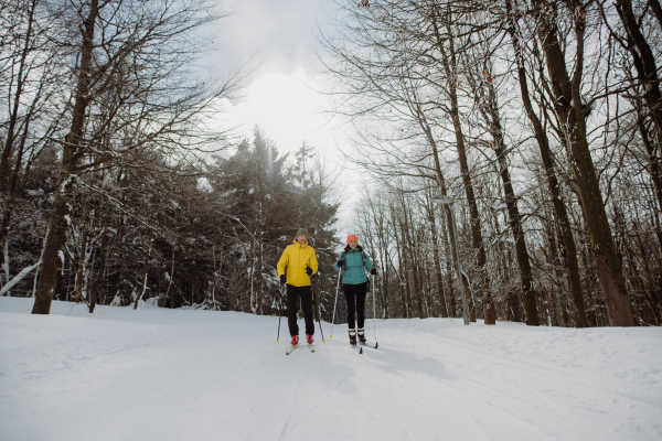 Senior couple skiing together in the middle of snowy forest