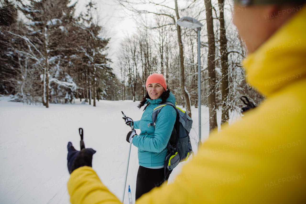 Rear view of senior couple skiing together in the middle of snowy forest.