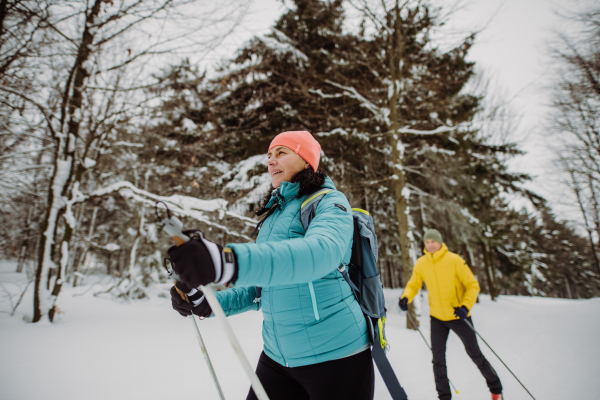 Senior couple skiing together in the middle of snowy forest