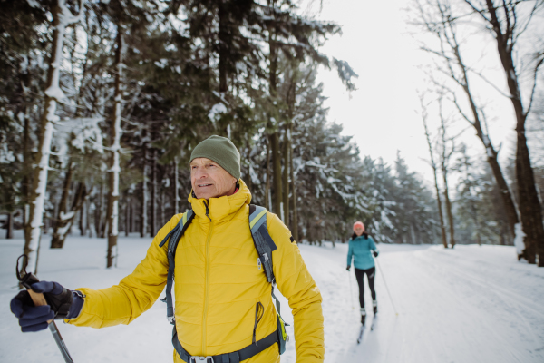 Senior couple skiing together in the middle of snowy forest