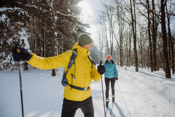 Senior couple skiing together in the middle of snowy forest