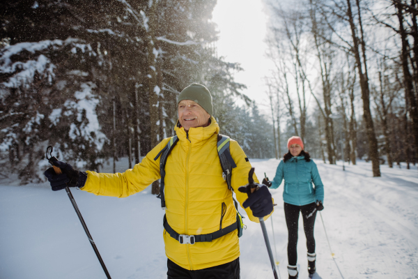 Senior couple skiing together in the middle of snowy forest