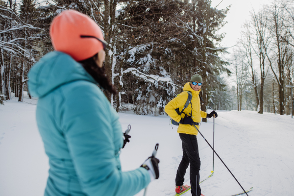 Senior couple skiing together in the middle of snowy forest