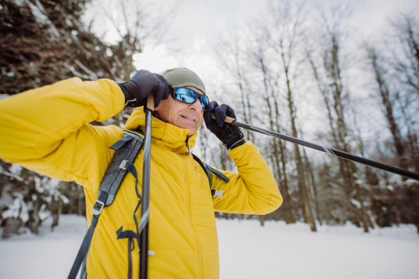 Senior man putting on snow glasses,preparing for ride in forest.