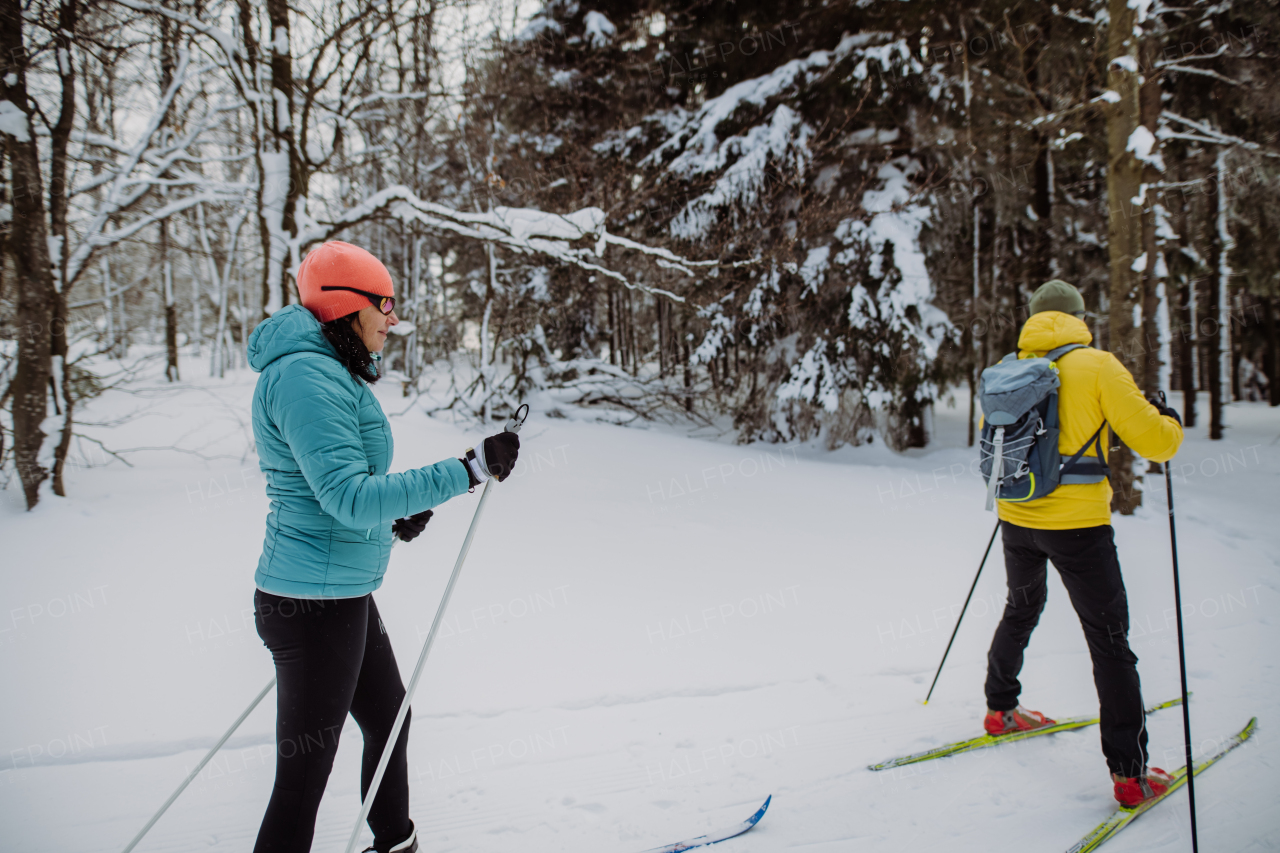 Senior couple skiing together in the middle of snowy forest