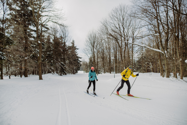 Senior couple skiing together in the middle of snowy forest